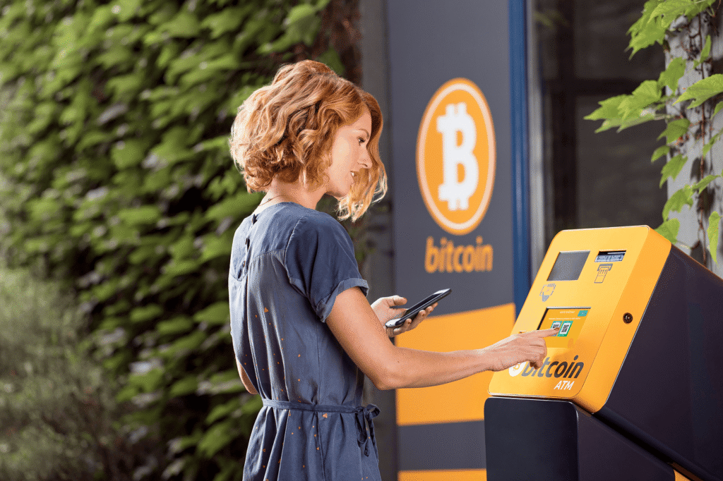 A woman withdrawing cryptocurrency from a Bitcoin ATM